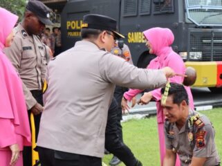 Kapolres Brebes AKBP Achmad Oka Mahendra menyiramkan air bunga kepada anggotanya yang naik pangkat. (Humas Polres Brebes)