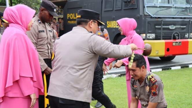 
					Kapolres Brebes AKBP Achmad Oka Mahendra menyiramkan air bunga kepada anggotanya yang naik pangkat. (Humas Polres Brebes)